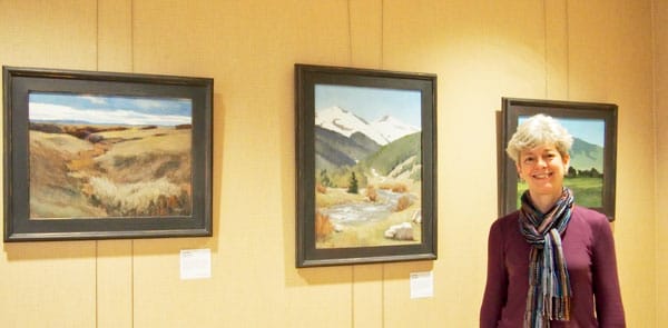 Photo of Sue with paintings that hang in Porter Adventist Hospital.