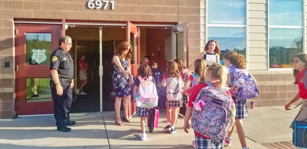 Photo of sheriff and school director greeting kids