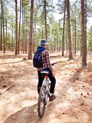 Photo of RCHS Aidan Malensek mountain biking and bringing his telescope.