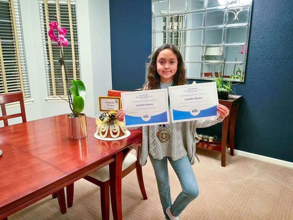 Photo of Isabella proudly celebrating her spelling bee win.
