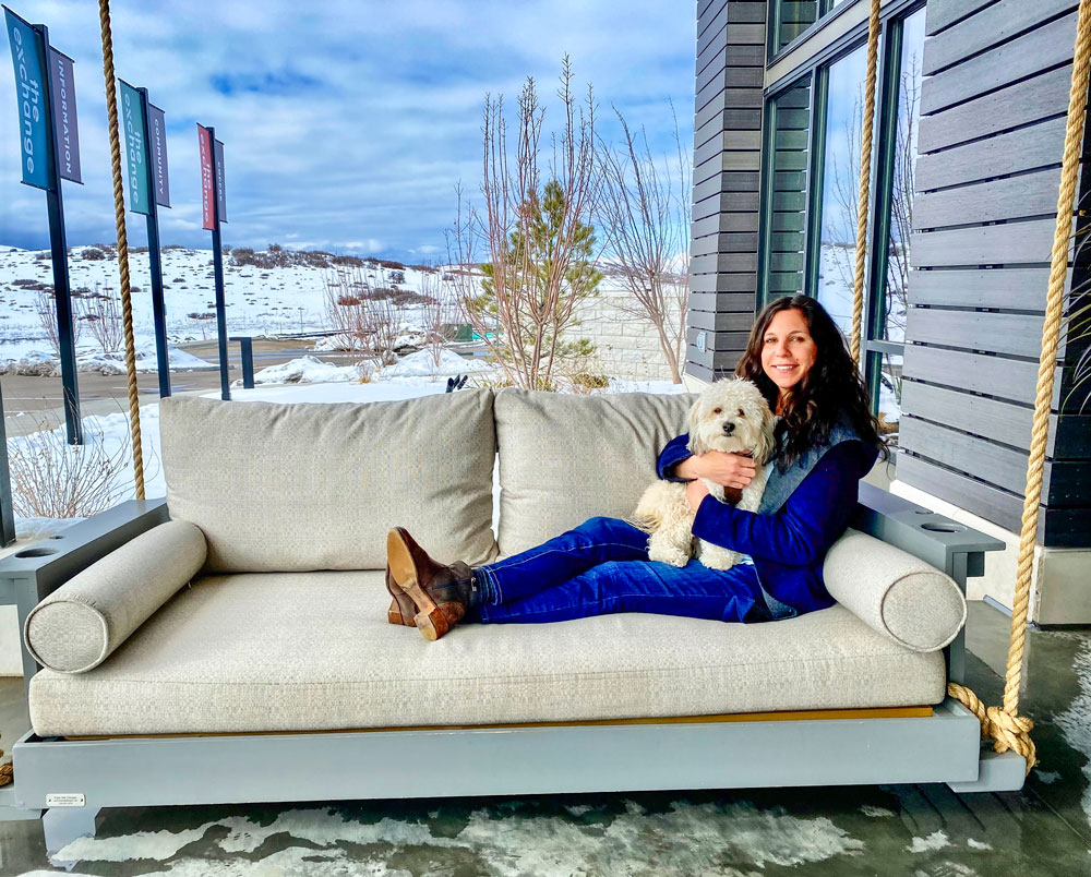 Photo of Dana Jevarjian and her dog, Benji, on the porch swing outside The Exchange Coffee + Conversation