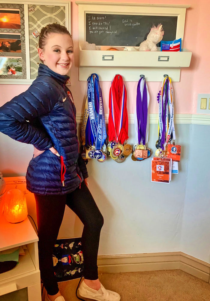 Photo of Autumn Hall posing at home with her medals.