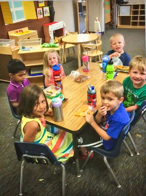 Photo of Caleb M. (top right) making a face at the camera during preschool snack