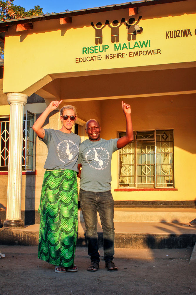 Photo of Megan Mathis and Hudson Mwale in front of RiseUp Malawi’s facility they built.