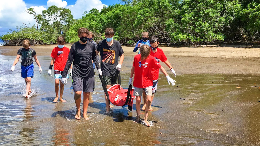 Photo of students carrying a juvenile hawksbill turtle.