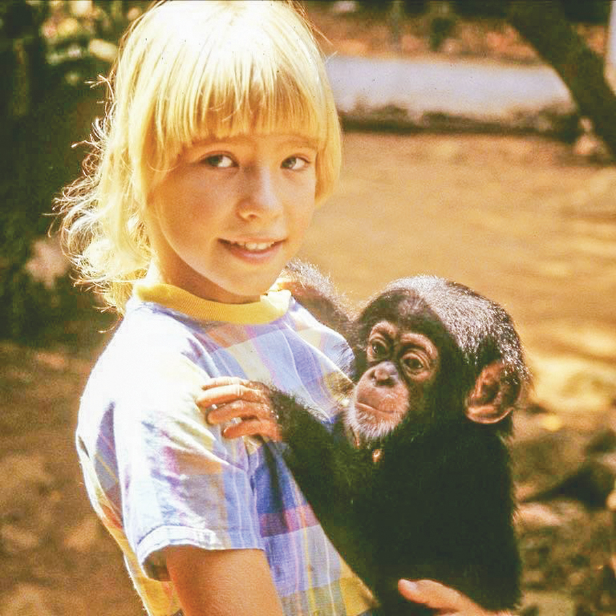 Photo of Nine-year-old Erika Tinker holds an orphaned chimpanzee, Matilda.
