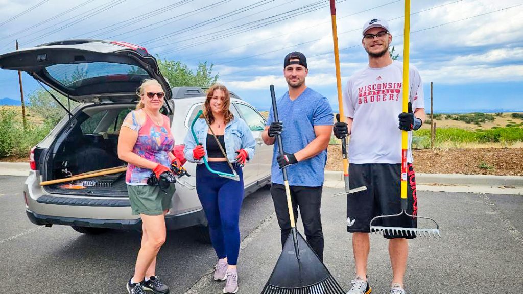 Photo of Millennial volunteers joining their former boss to help pull weeds.