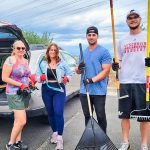 Photo of Millennial volunteers joining their former boss to help pull weeds.