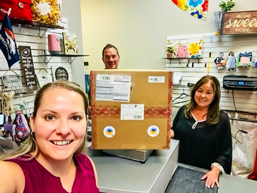 Photo of Yulia Boozer (left) receives help from Castle Pines Postal Center owner John Tartz, 