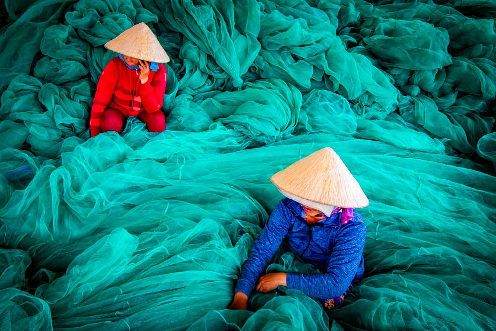 Photo of workers mend and maintain their fishnets