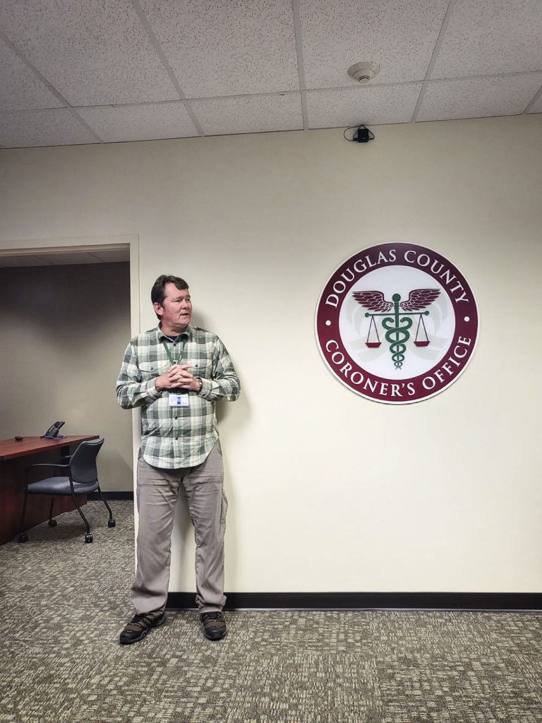 photo of man standing next to coroners office