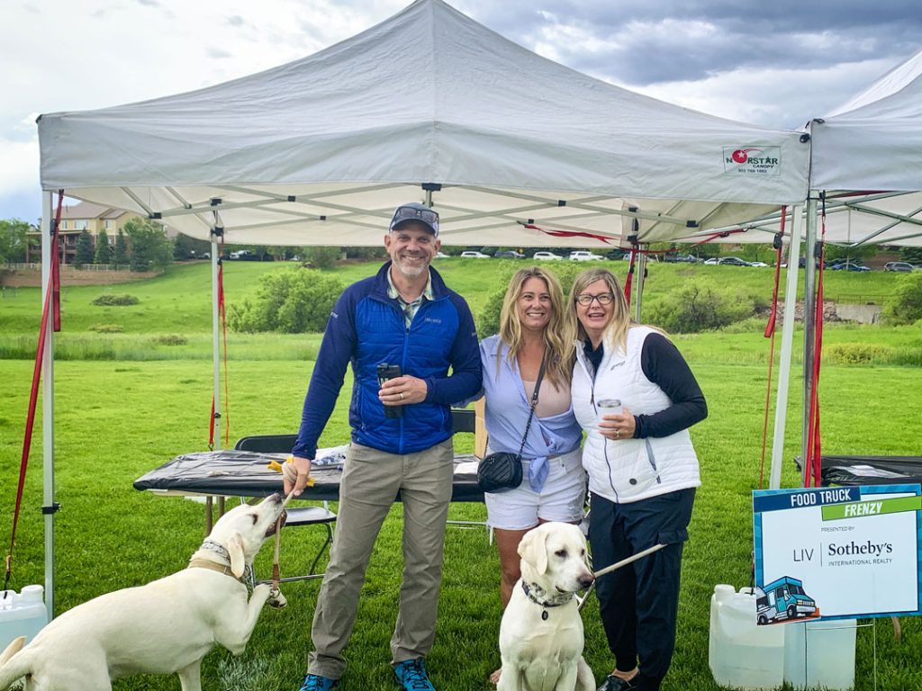 photo of three people and dogs under tent