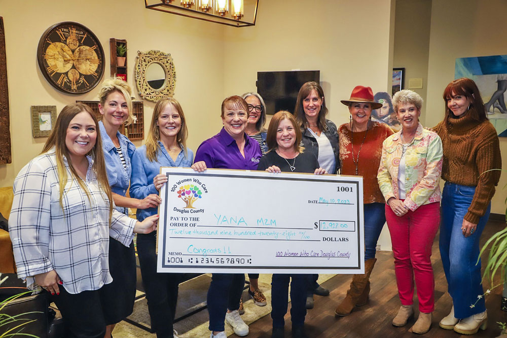 group of ladies holding large check to their charity