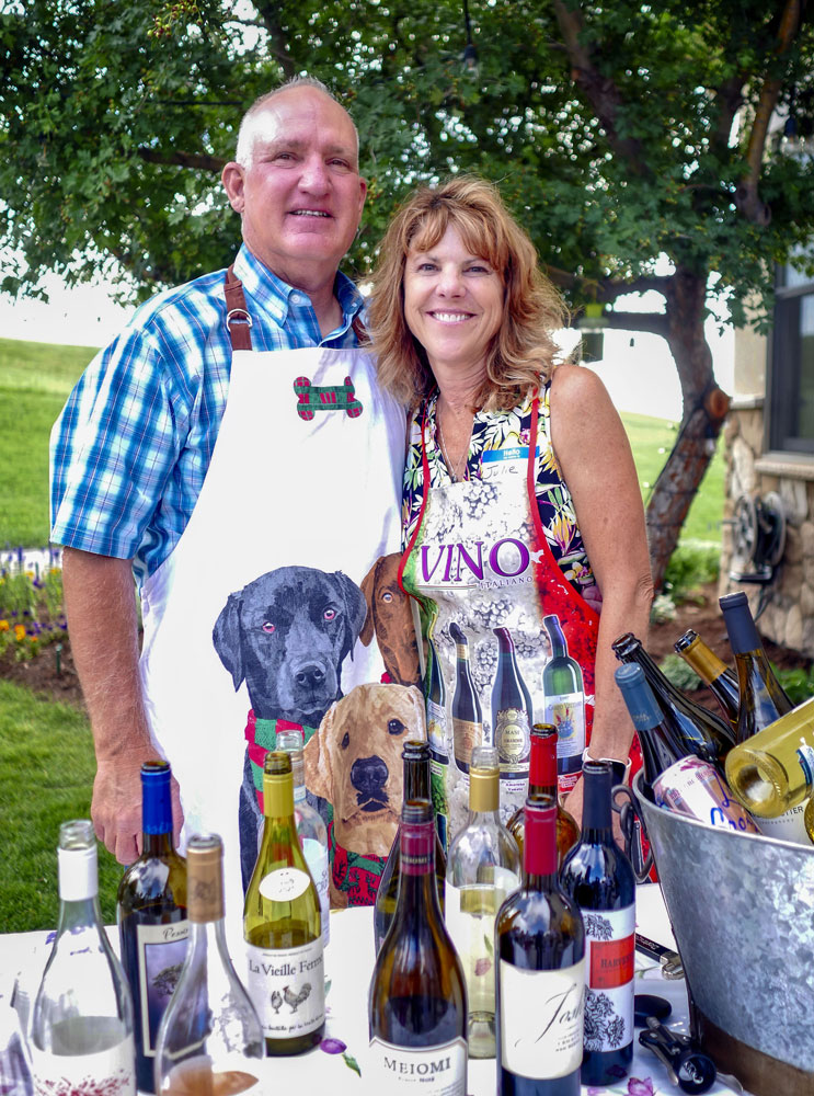 couple stand behind table with bottles of wine