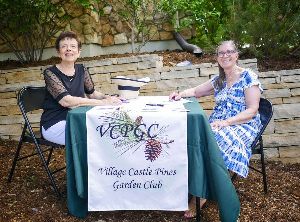 two ladies sit at table for the village castle pines garden club