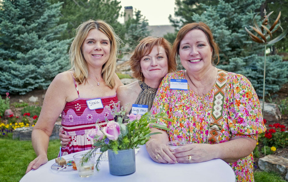 three ladies standing at table in garden