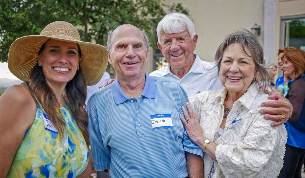 four adults posing for photo outside