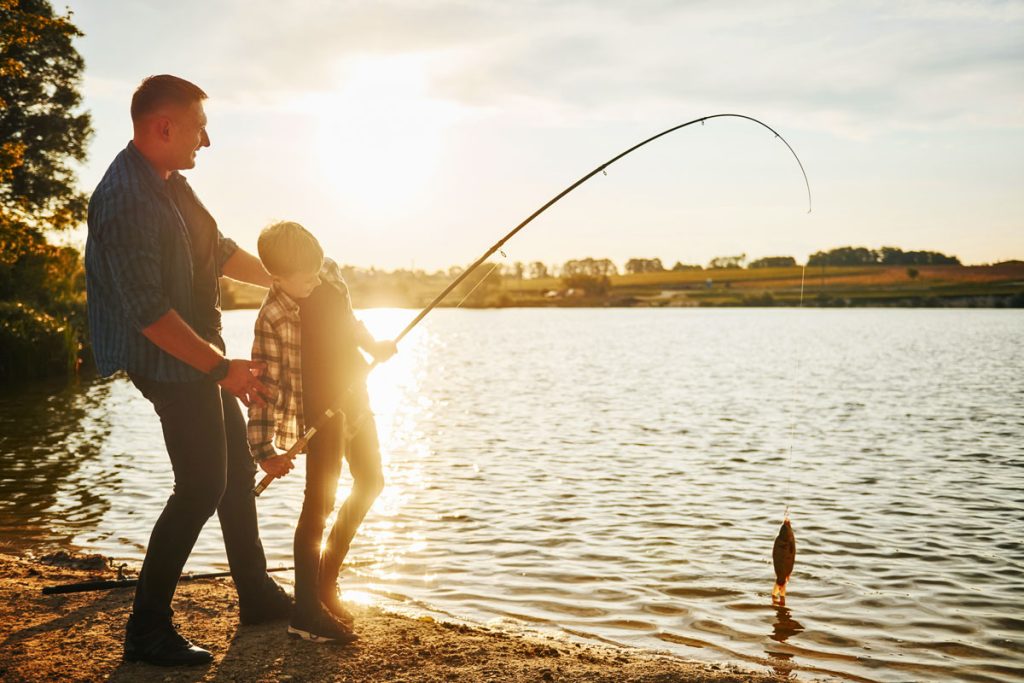 man and son fishing at sunset