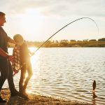 man and son fishing at sunset