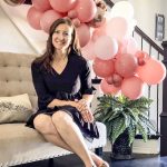 lady sitting at home with balloons behind her