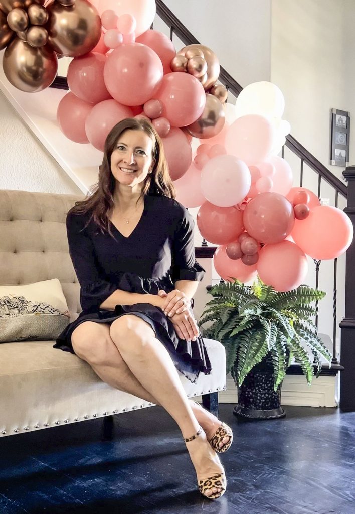 lady sitting at home with balloons behind her