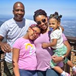 family posing at top of mountain