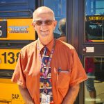 older man stands in front of bus