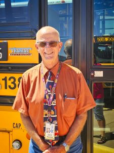 older man stands in front of bus