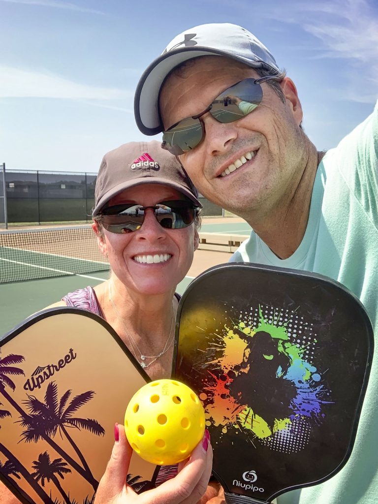 couple with pickleball rackets