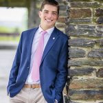 young man in suit and tie in front of rock wall