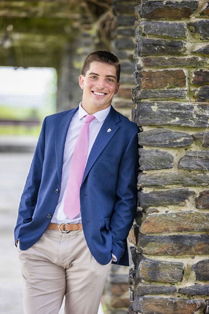 young man in suit and tie in front of rock wall