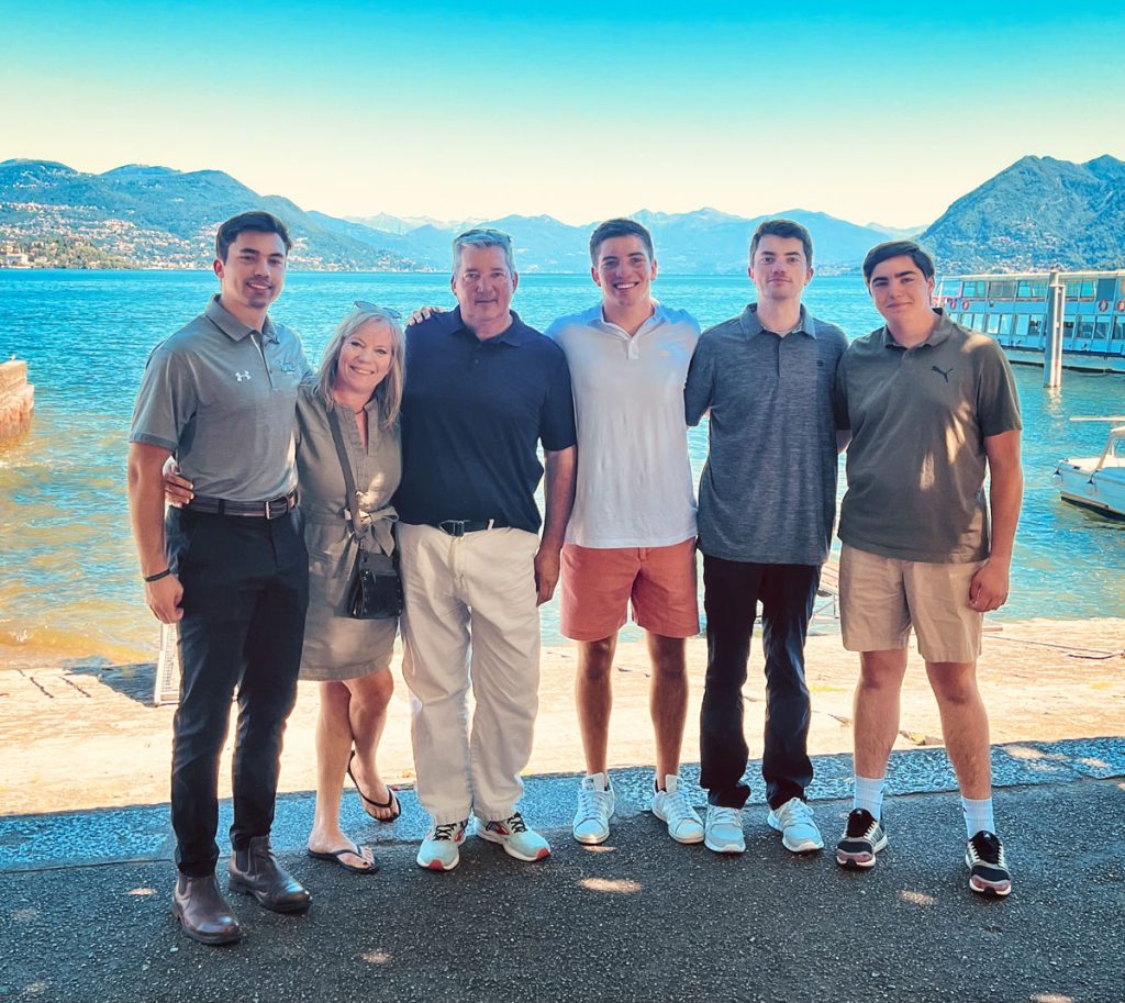 family standing in front of water and mountains