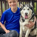 boy and dog outside next to each other