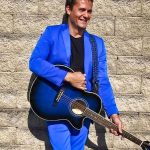 man in blue suit holding guitar