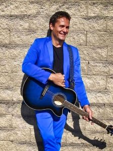 man in blue suit holding guitar