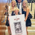 four people in formal wear holding honors