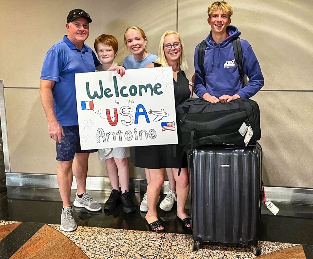 five people standing inside airport holding sign