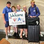 five people standing inside airport holding sign