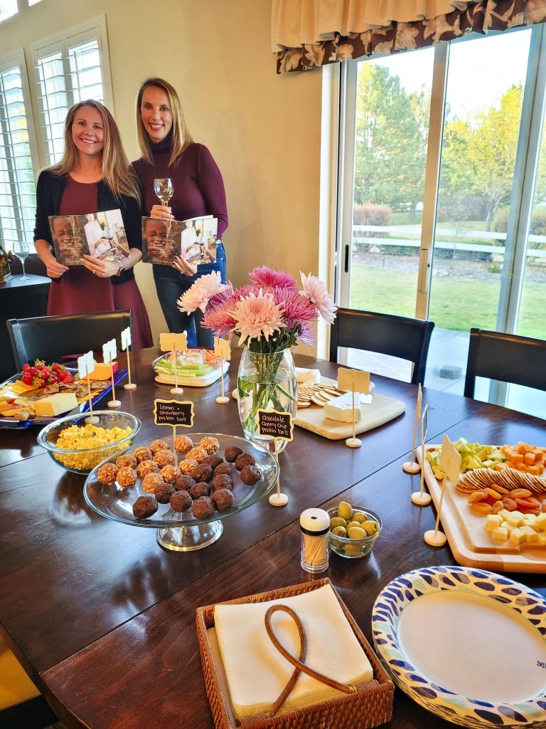 ladies standing next to table full of food