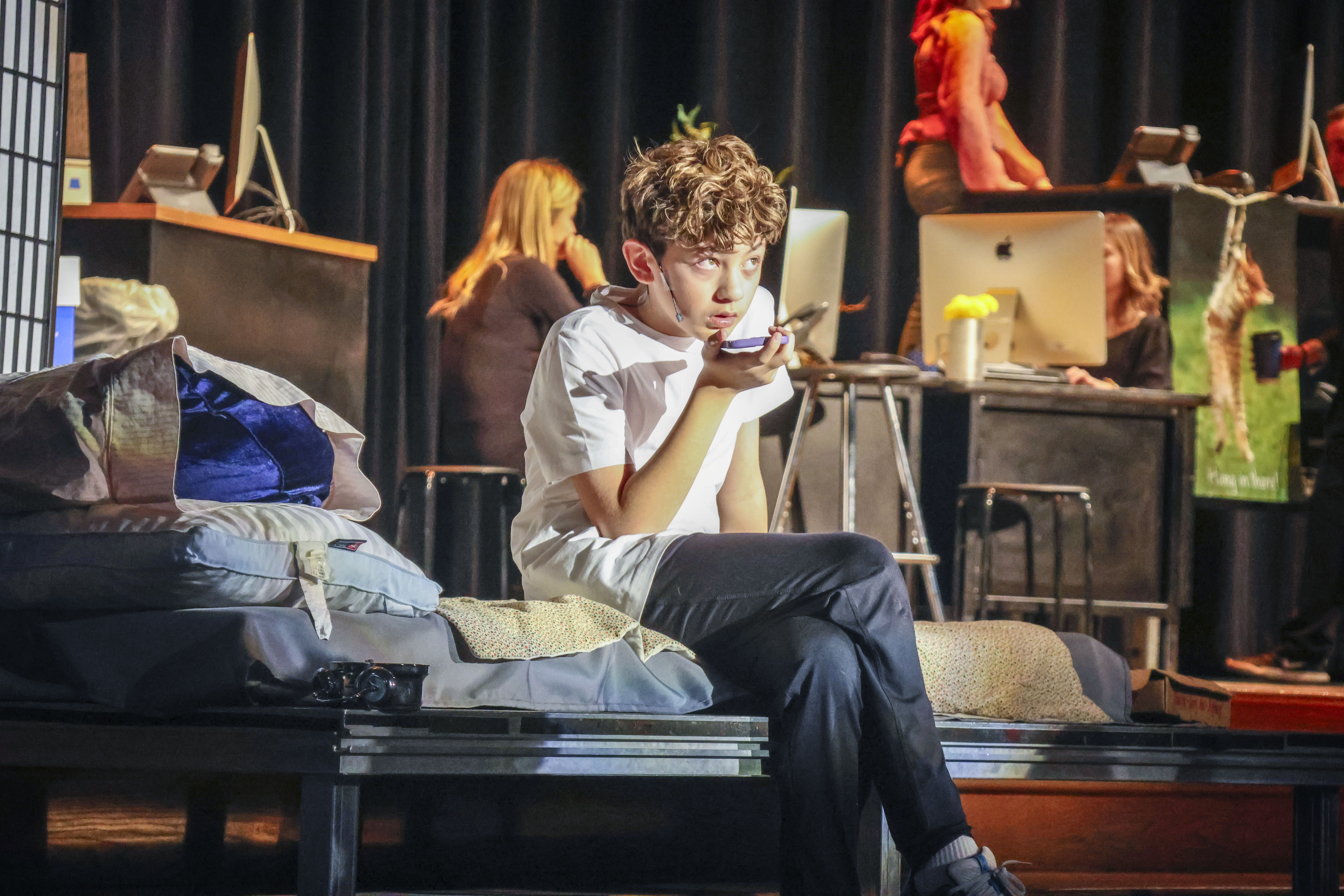 male student holding phone on stage