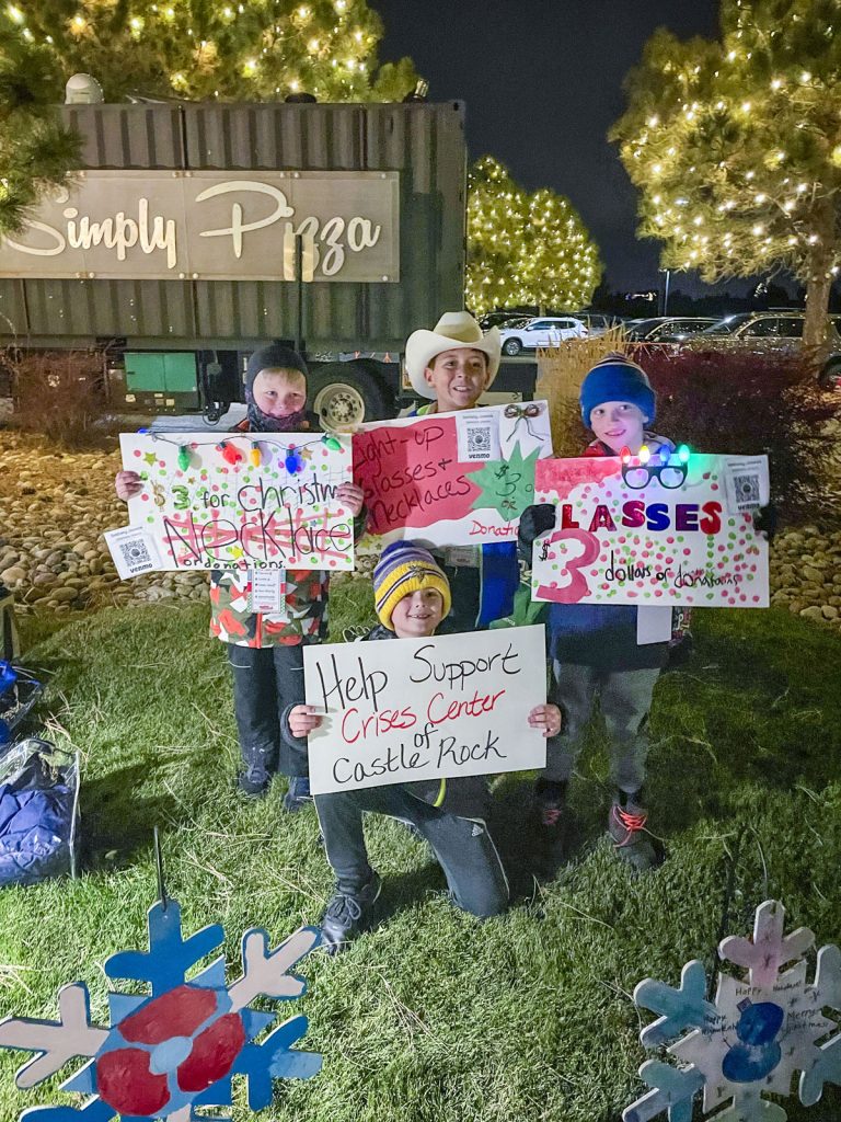 four kids stand outside holding paper