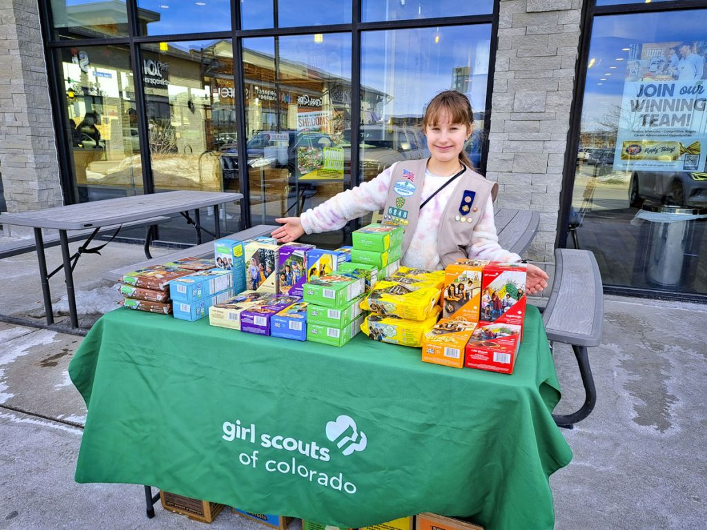 girl behind table full of cookies