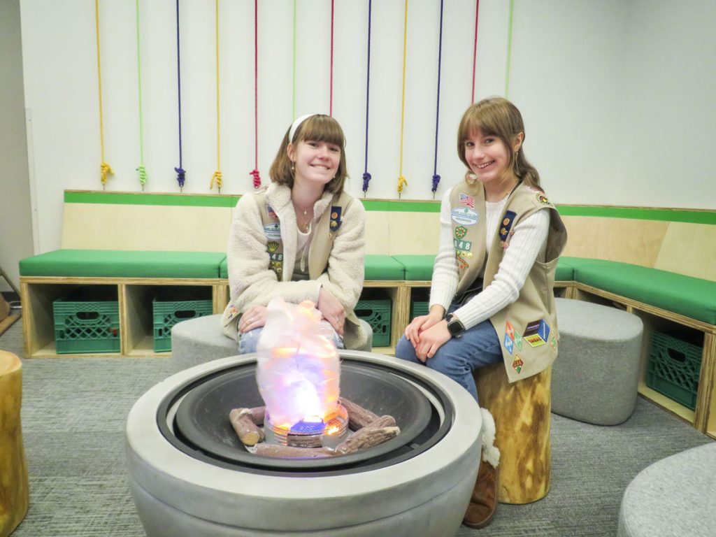 two girls sitting by faux fire