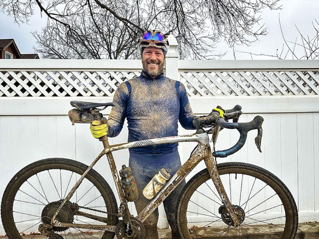 smiling man holding muddy bicycle