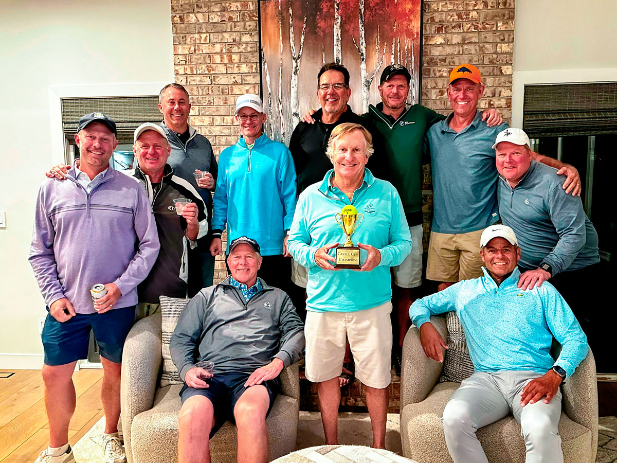 group of men in living room, one holding tennis trophy