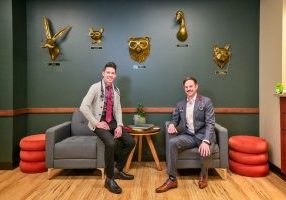 Aaron Block, M.D. (right) and John Waters (left) opened The Cove Concierge Medicine in Castle Rock in 2024. The golden heads on the wall are characters from Canadian author Jessica Hiemstra. Dr. Block and John consider them “our Cove Guardians” as they bring a sense of nature and wonder to the waiting room.