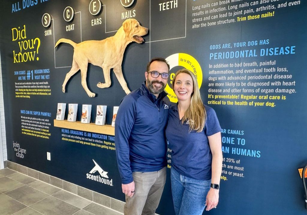 Jim and Christy Boswell in front of the Knowledge Wall at their Scenthound location in Parker.