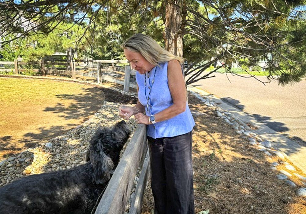 Susan Tucker greeting a neighborhood dog, Delaney, in The Retreat.