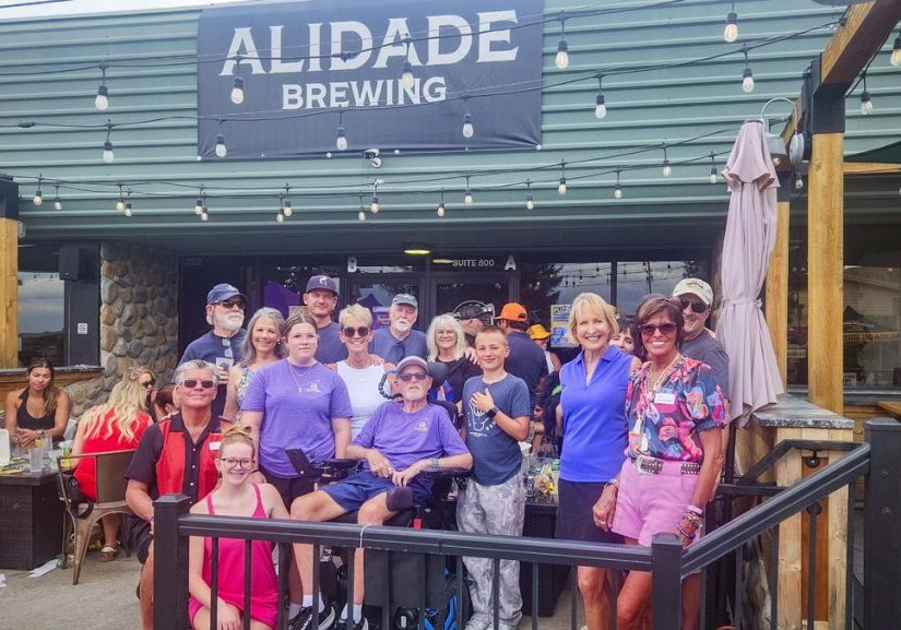 Mark Ryan surrounded by his wife Diane (white tank top), family and friends at the first annual Paul’s Mystery Ship to End ALS’s Summer Bash at Alidade Brewery in Castle Rock. Director Executive Treasurer Paul Cathey (bottom left); Founder and President Bonnie Dannels (bottom right).